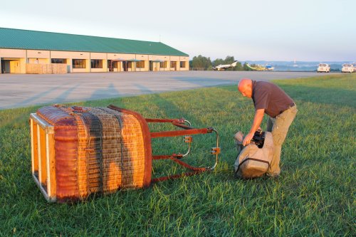 Sunrise at the Taney County Airport.  Rodney Williams, pilot, installing the burner onto the basket in preparation of early morning flight